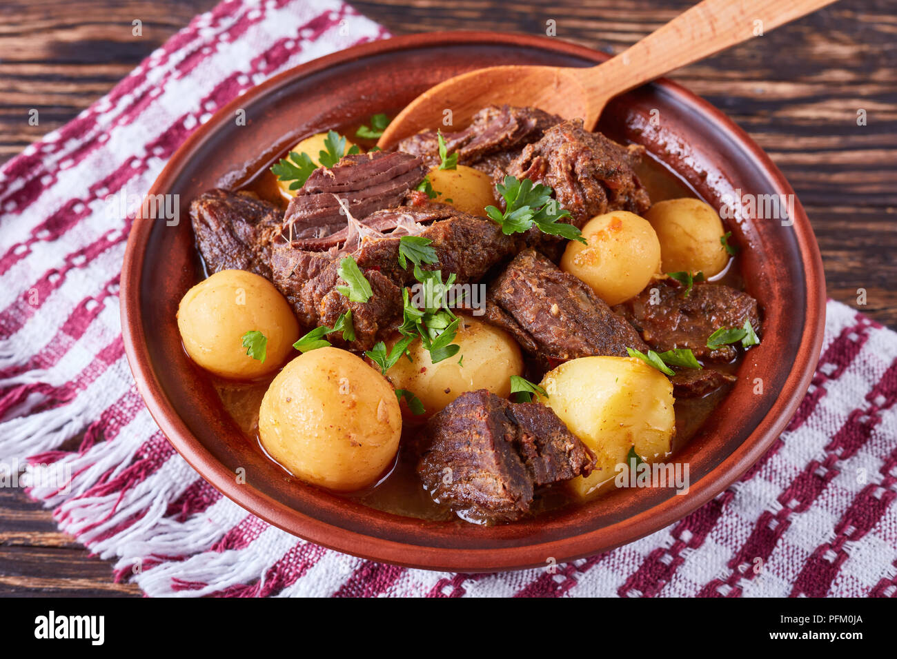 Ragoût de boeuf chaud avec de tendres cubes de viande, pommes de terre nouvelles, ensemble l'oignon et les herbes dans un bol d'argile sur la vieille table en bois rustique avec une cuisine irlandaise, serviette, hor Banque D'Images