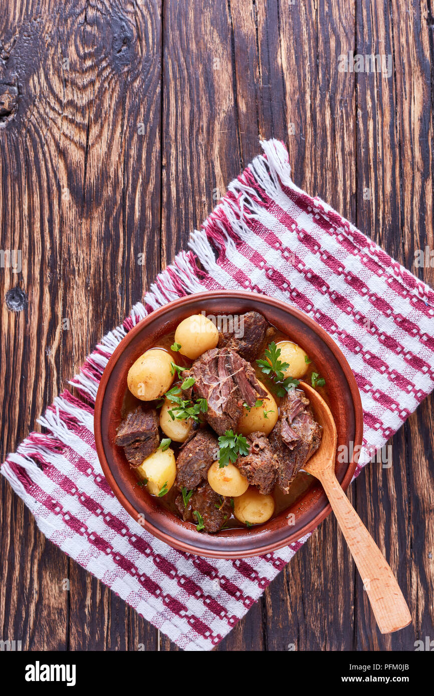 Ragoût de boeuf chaud avec de tendres cubes de viande, pommes de terre nouvelles, ensemble l'oignon et les herbes dans un bol d'argile sur la vieille table en bois rustique avec une cuisine irlandaise, serviette, ver Banque D'Images