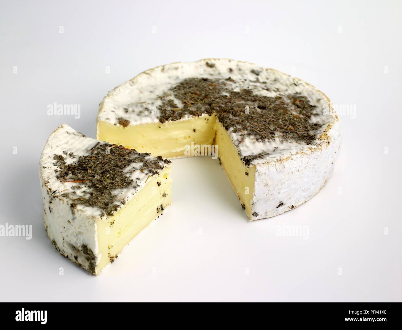 Rond et tranche de Pithiviers Français fromage au lait de vache avec écorce couverte de fines herbes séchées Banque D'Images