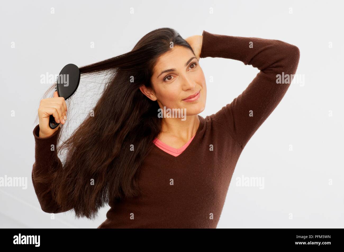 Woman in brown v-neck sweater brosser ses cheveux Banque D'Images
