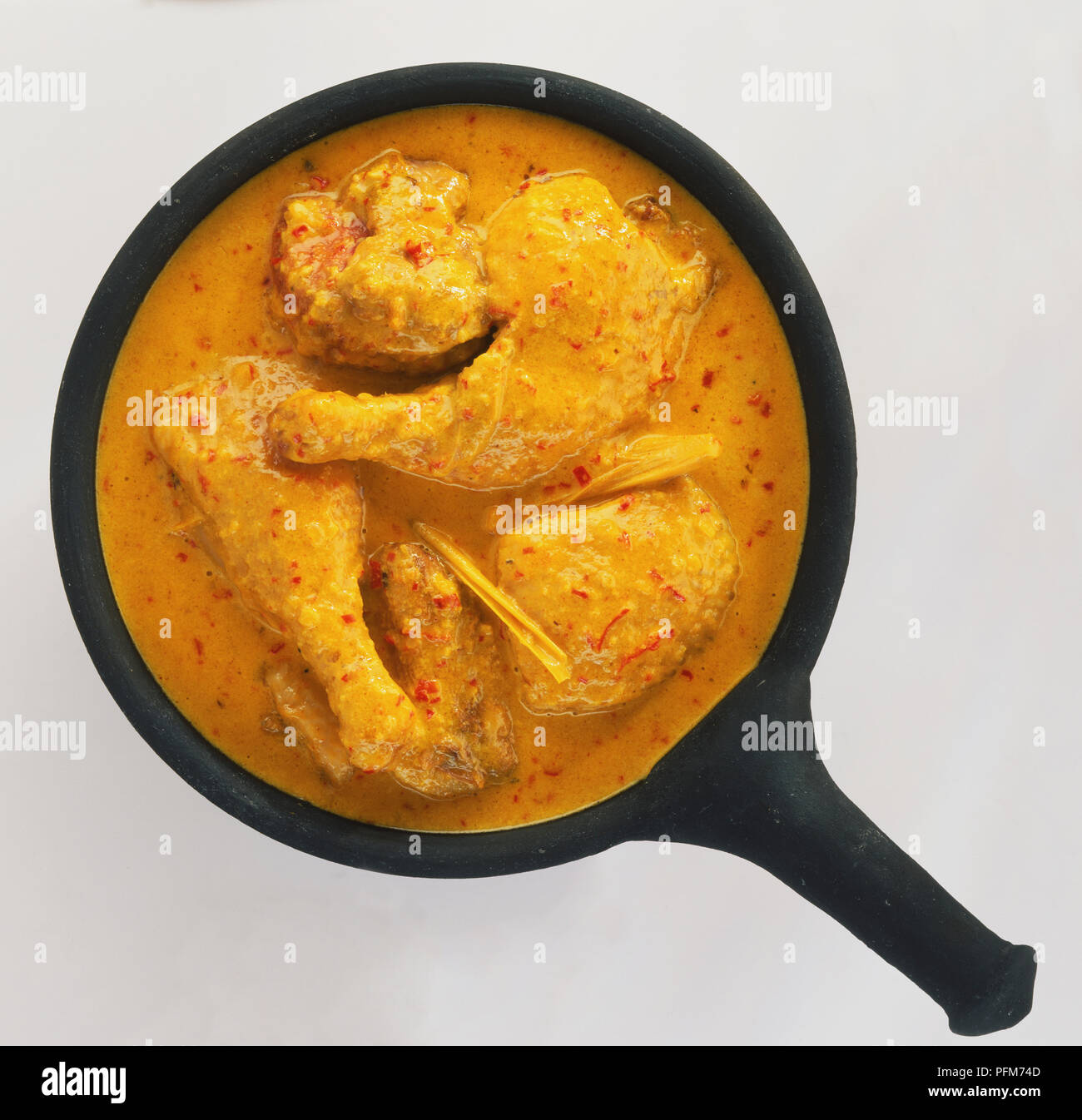 Ailes de canard en sauce riche de coco saupoudrée de piment rouge, vue de dessus. Banque D'Images