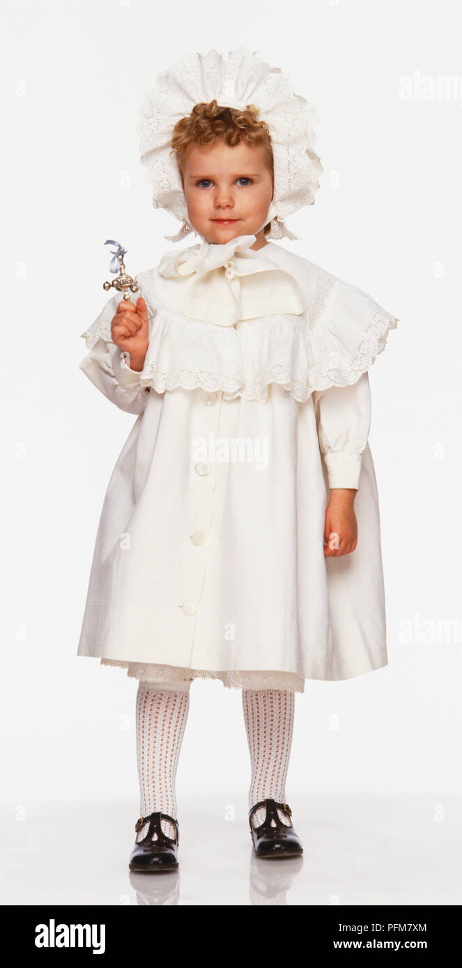 Un enfant portant un manteau blanc et bonnet à froufrous, du début du xxe siècle Banque D'Images