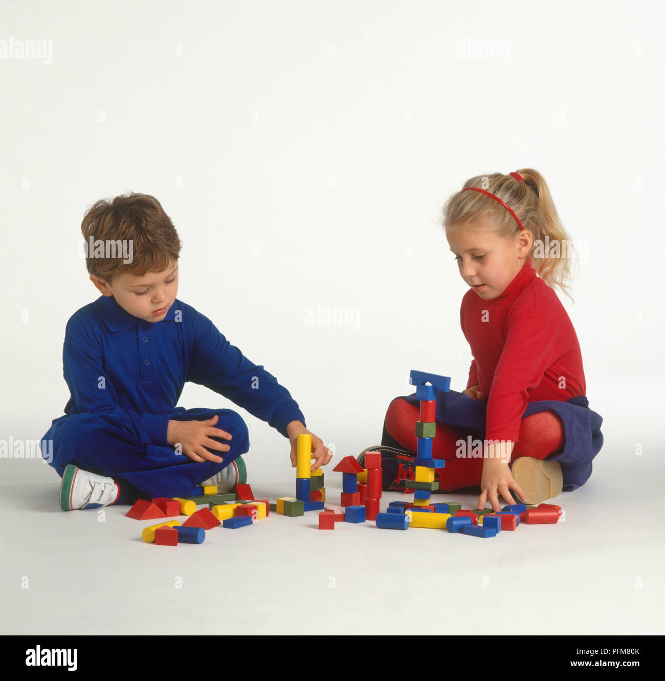 Fille et garçon assis sur le plancher et en jouant avec les blocs de construction Banque D'Images