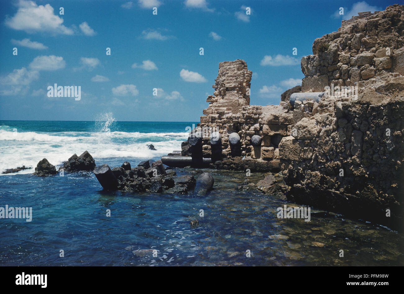 Israël, ruines romaines au bord de la mer avec des vagues fouettant sur eux, à Ceasaria, autrefois le plus grand port de la ville romaine antique au Moyen-Orient. Banque D'Images