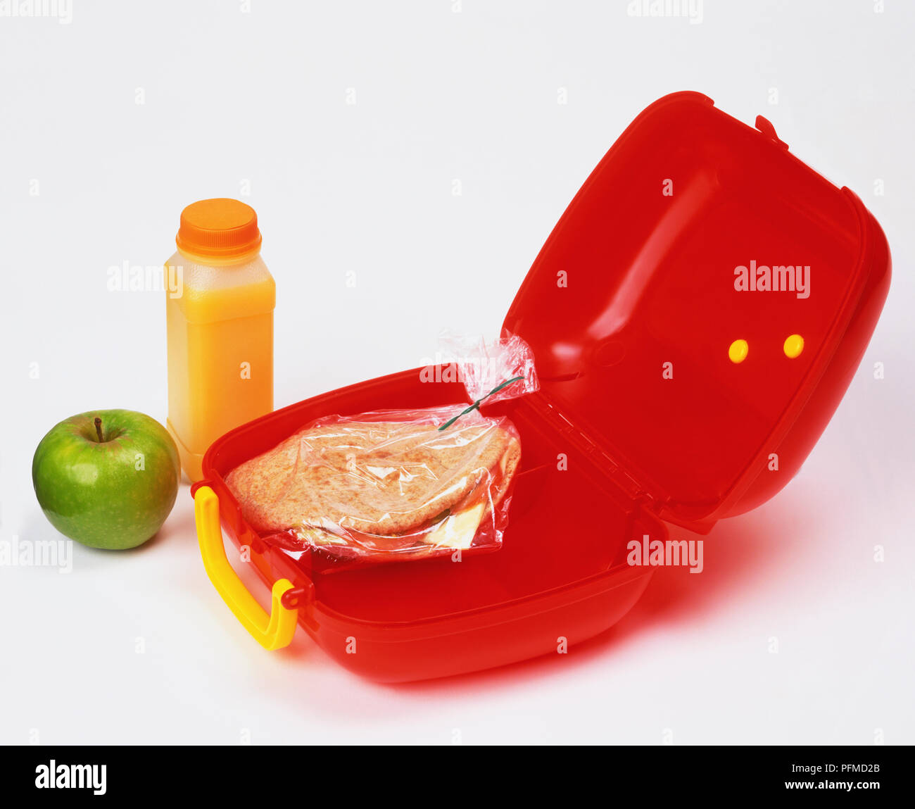 Pain Pitta en sandwich lunch rouge ouvert, une bouteille de jus d'orange et vert pomme sur le côté. Banque D'Images