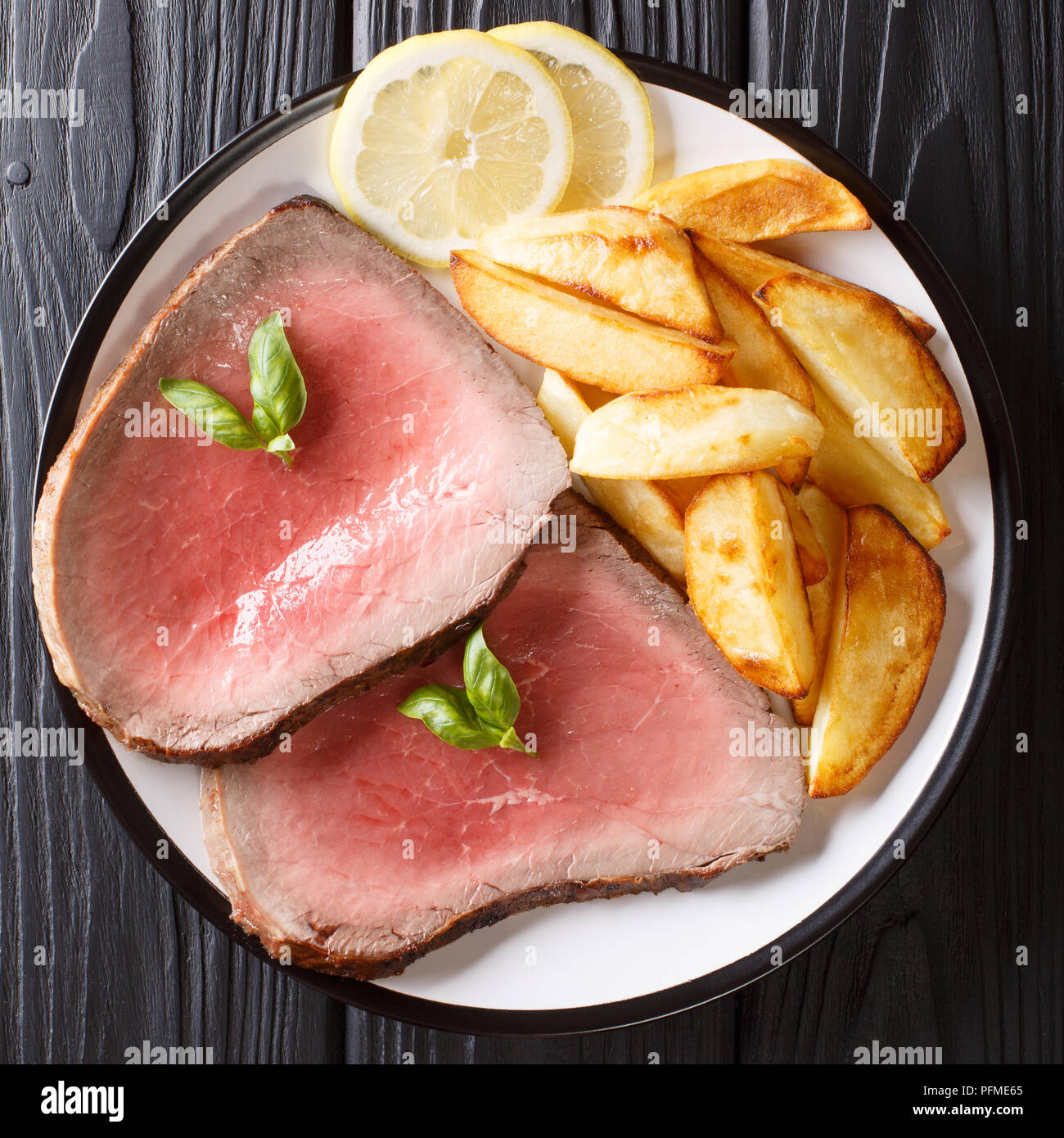 Pavé de boeuf rôti moyen avec des pommes de terre sur une plaque sur un tableau noir. haut Vue de dessus Banque D'Images