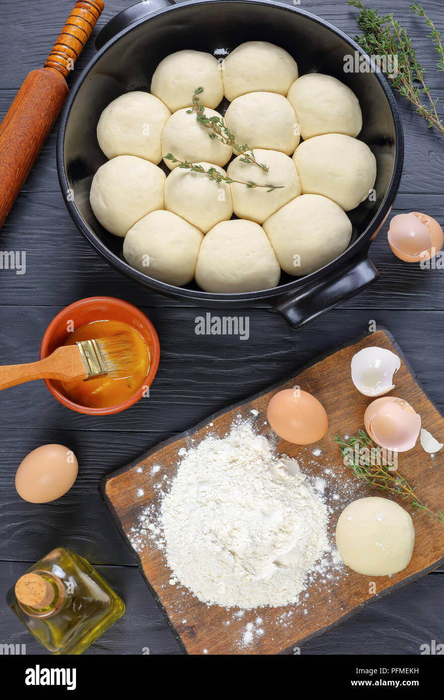 Douce et moelleuse tarte de petits pains dans le plat de cuisson avec la pâte, de la farine et des oeufs sur une planche à découper et le matériel roulant sur l'axe de travail de cuisine en bois haut, vertical Banque D'Images