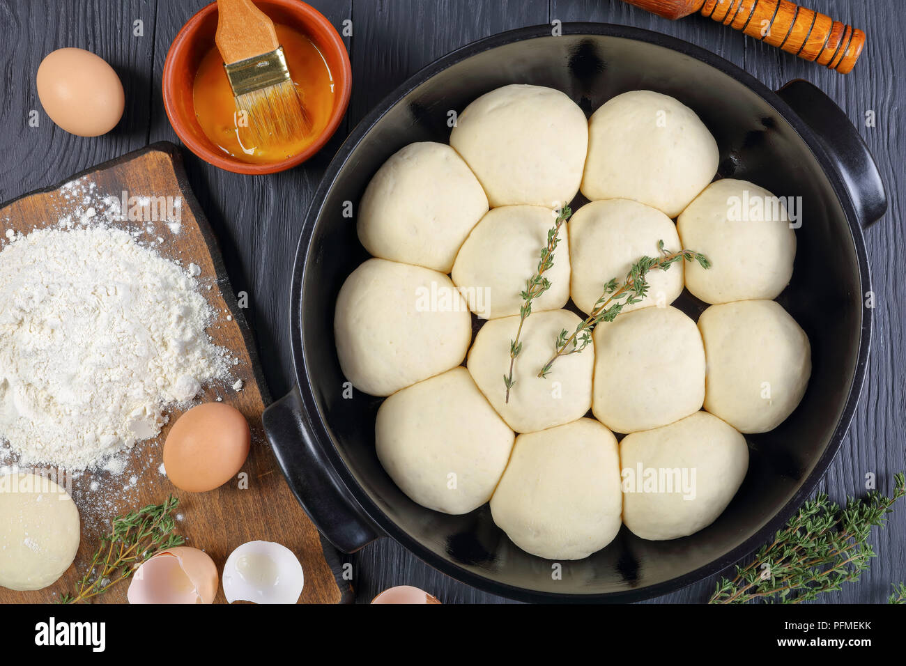 Douce et moelleuse tarte brioches dîner dans le plat de cuisson avec la pâte, de la farine et des oeufs sur une planche à découper, l'huile d'olive, rouleau à pâtisserie en bois sur une table de cuisine, vue Banque D'Images