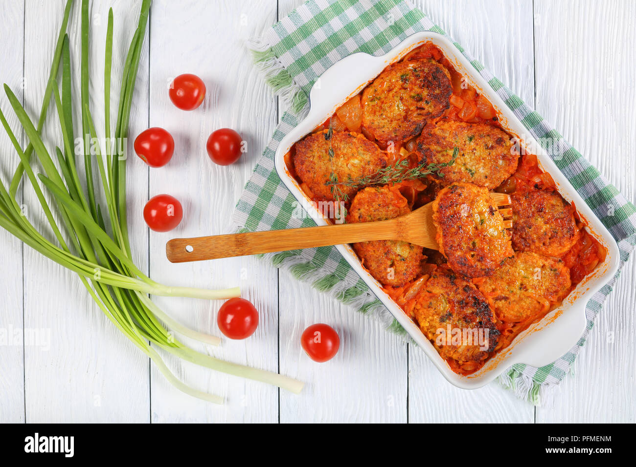 Couscous cakes avec l'oignon, les carottes et la sauce tomate dans le plat de cuisson avec l'oignon vert et les tomates de table en bois, une cuisine méditerranéenne recette, v Banque D'Images