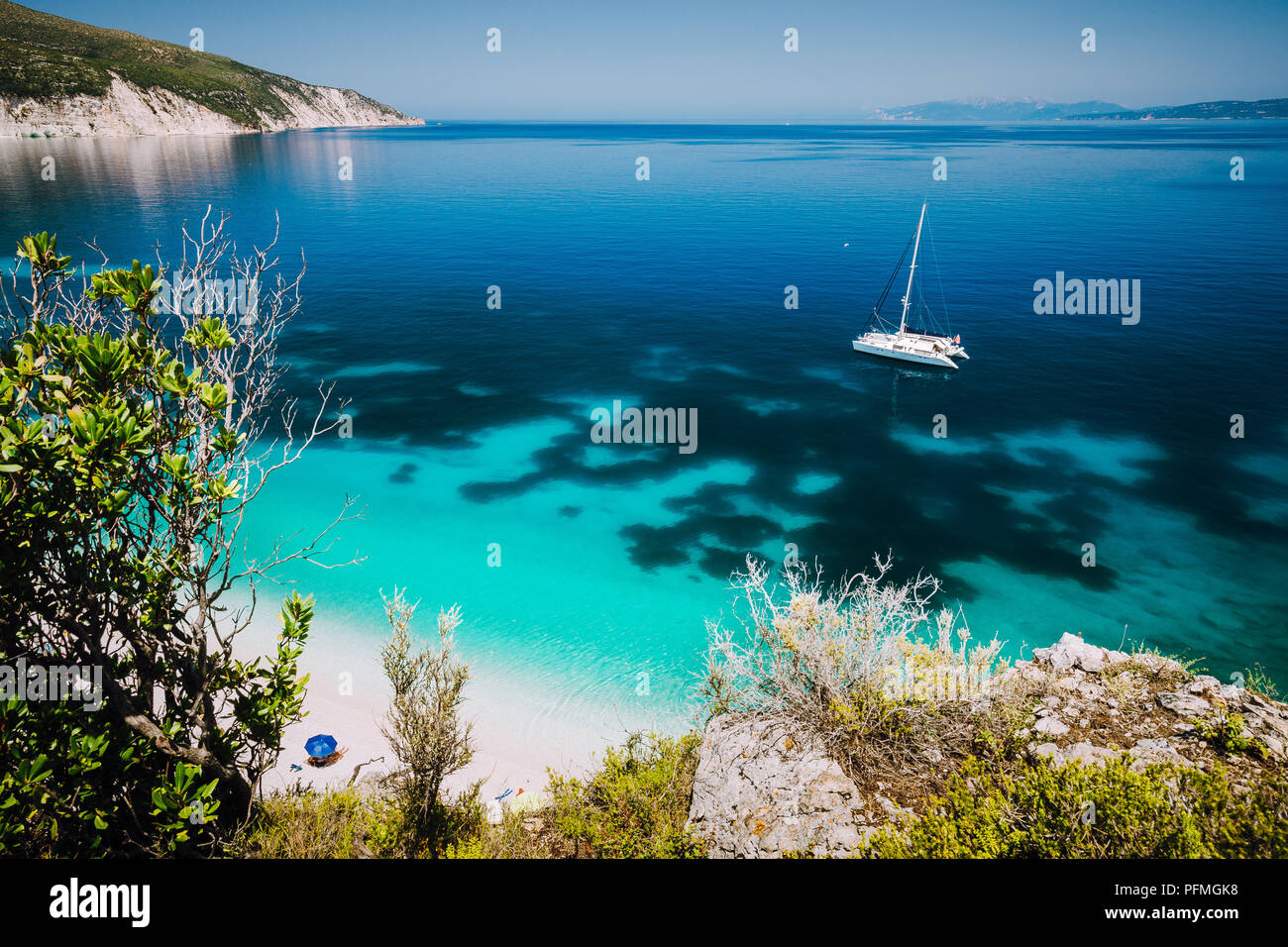 Fteri beach, île de Céphalonie Céphalonie, Grèce. Yacht à voile blanc bleu clair l'eau de mer. Les touristes sur plage de sable près de lagune azure Banque D'Images