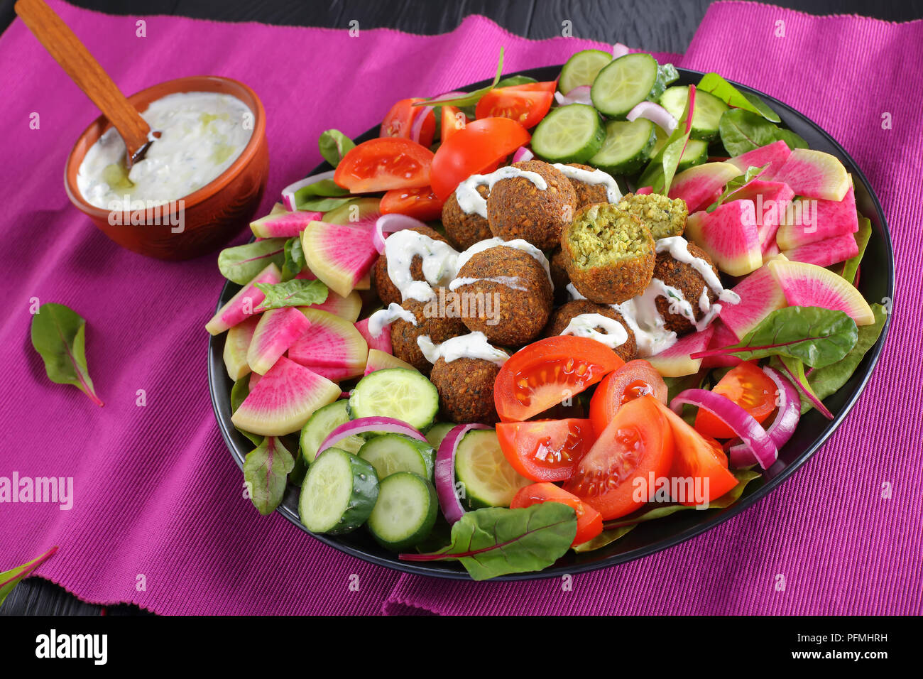 Délicieux avec des boules de falafel sauce yaourt grec sur la plaque avec légumes salade de melon d'eau colorée, radis, feuilles de bette à carde et les tranches de tomate concombre tza. Banque D'Images