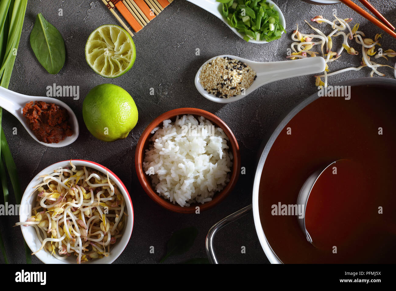 Ingrédients pour la soupe miso sur fond de béton - dashi miso à coller dans le moule, la pâte de miso, graines de sésame, du riz vapeur, épinards, fèves germées, vert Banque D'Images