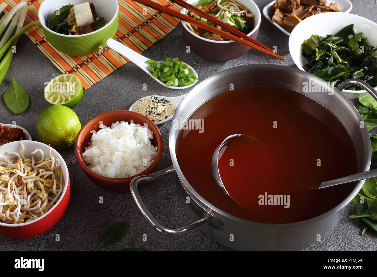 La soupe miso dans un bol avec des baguettes. Ingrédients sur table béton - le tofu, le miso, pâte d'algue wakame, le riz, les champignons shiitake, les germes, les verts et Banque D'Images