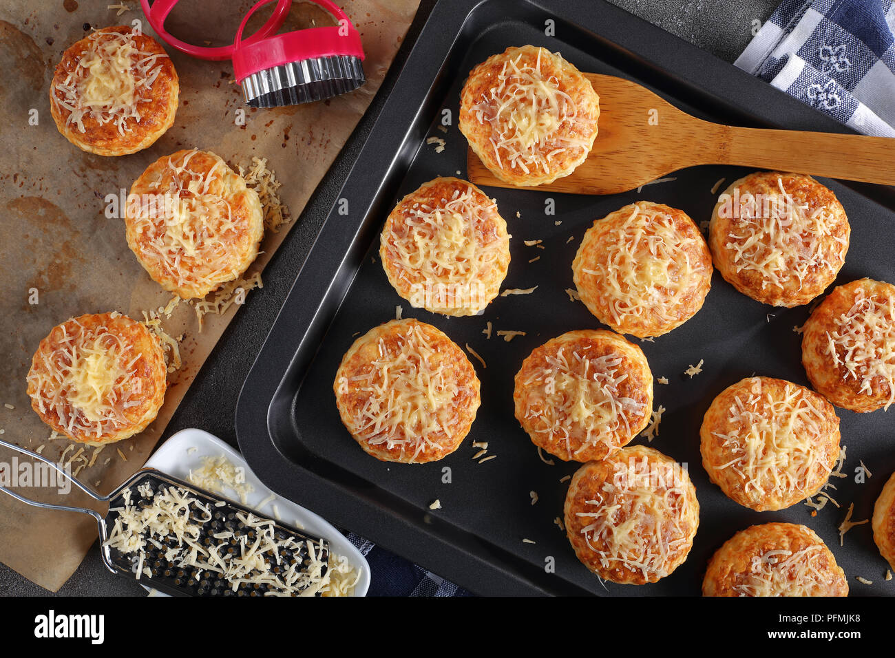 Des délicieux scones anglais saupoudré de fromage râpé sur une plaque et sur du papier à l'emporte-pièce, vue de dessus, close-up Banque D'Images