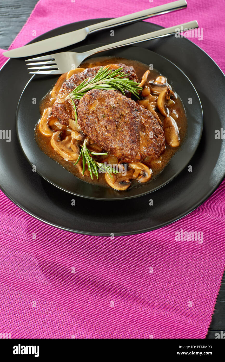 Partie de sex salé les steaks juteux salisbury avec champignons sauce oignon délicieux servi sur les plaques noires avec couverts sur tapis de table, restaurant sty Banque D'Images