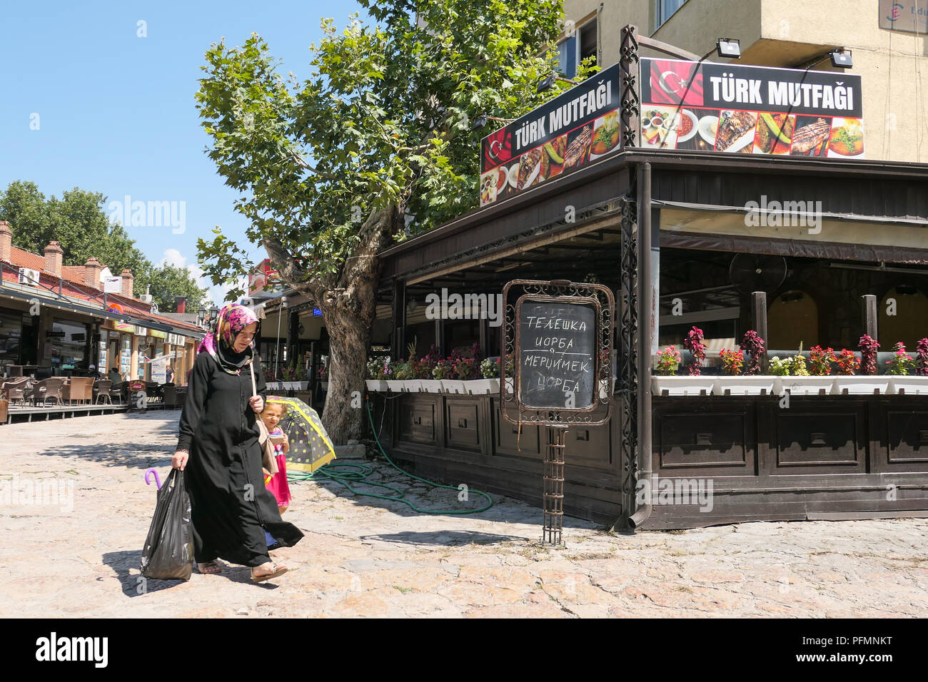Skopje Bazar - femme musulmane et petit enfant en passant devant une boutique ou restaurant turque, Skopje, Macédoine Banque D'Images
