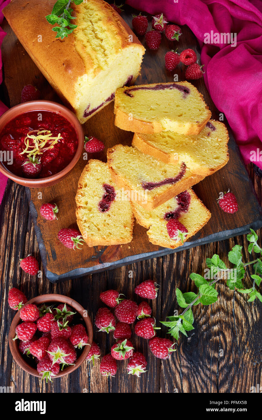 Quatre-quarts au citron avec confiture de framboises remplissant également connu sous le nom de gateau de voyage gâteau sur une vieille table en bois foncé, style rustique, une cuisine française, vertical vi Banque D'Images