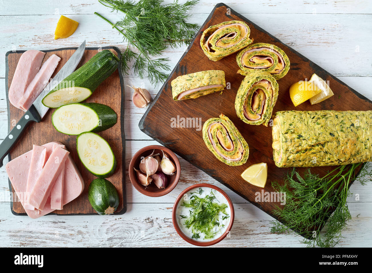 Close-up of delicious roulade de courgettes au fromage fondu et de jambon cuit, coupé en tranches sur une planche à découper, salé et sauce au yogourt ingrédients sur Banque D'Images