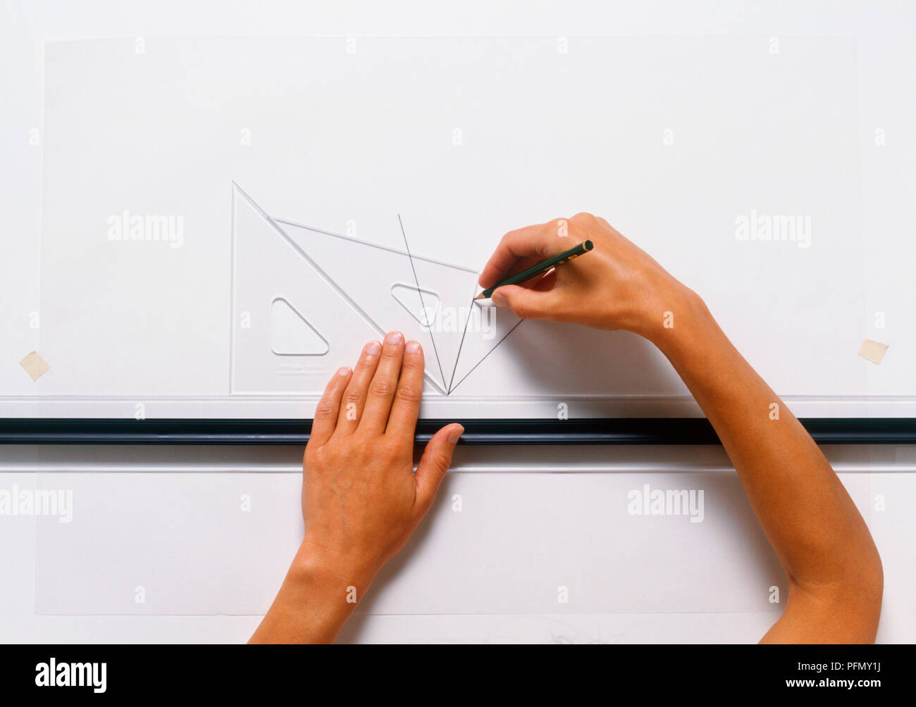 Boy drawing un angle à l'aide de deux triangles à angle droit et d'une règle Banque D'Images