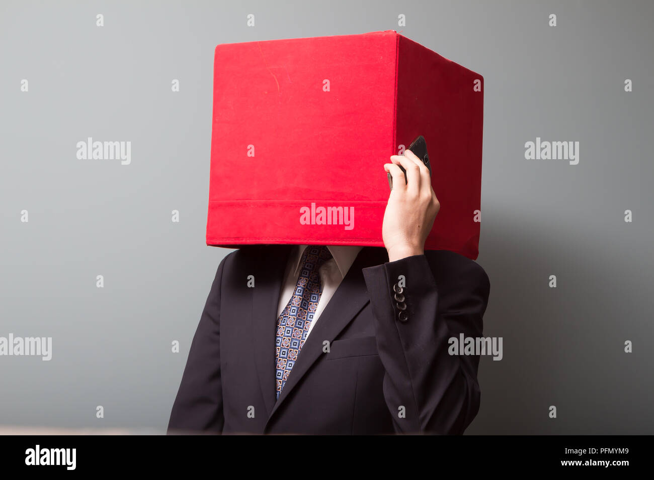 Homme portant costume et cravate abusiness avec une case rouge au lieu de la tête parle on mobile phone Banque D'Images