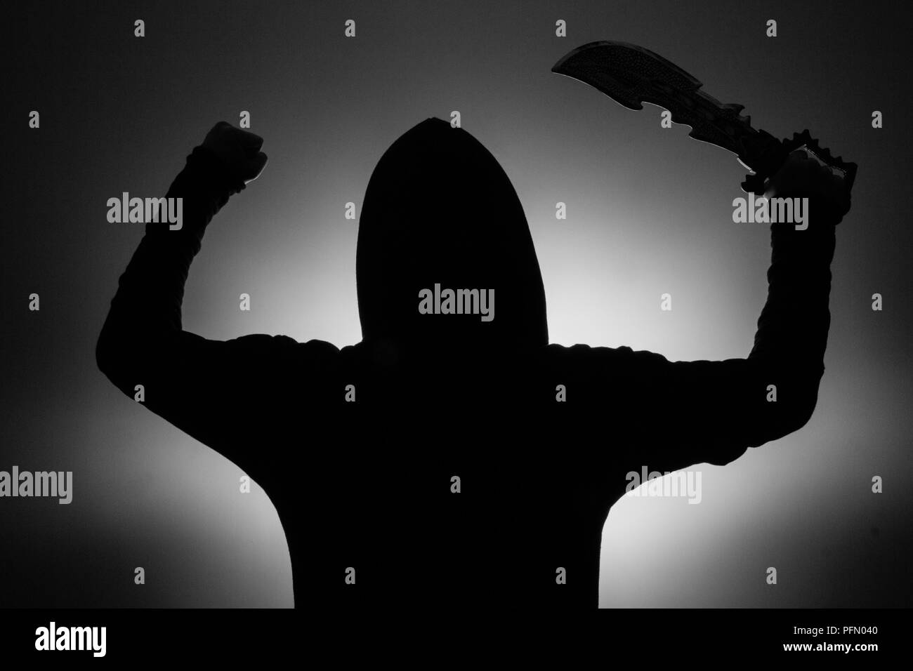 Photo en noir et blanc : silhouette d'un homme dans un capuchon tenant une épée dans une fantaisie accrocher soulevé dans l'air Banque D'Images