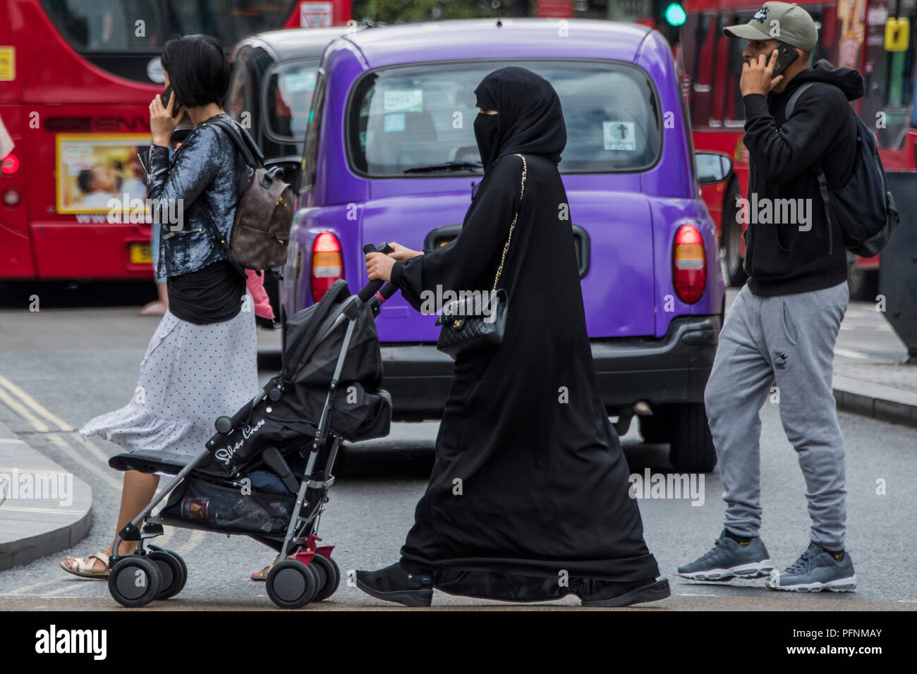 Londres, Royaume-Uni. Le 22 août, 2018. Une femme musulmane dans un hijab et burka pousse un landau dans Oxford Street - une vue normale dans la foule mêlée de shopping. Crédit : Guy Bell/Alamy Live News Banque D'Images