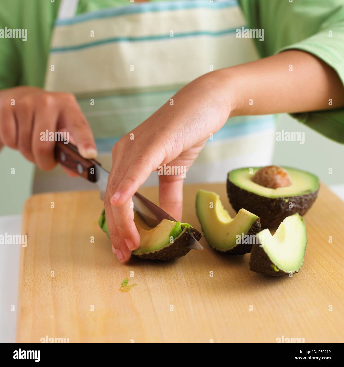 Garçon à l'aide de couteau de cuisine pour couper l'avocat sur planche à découper Banque D'Images