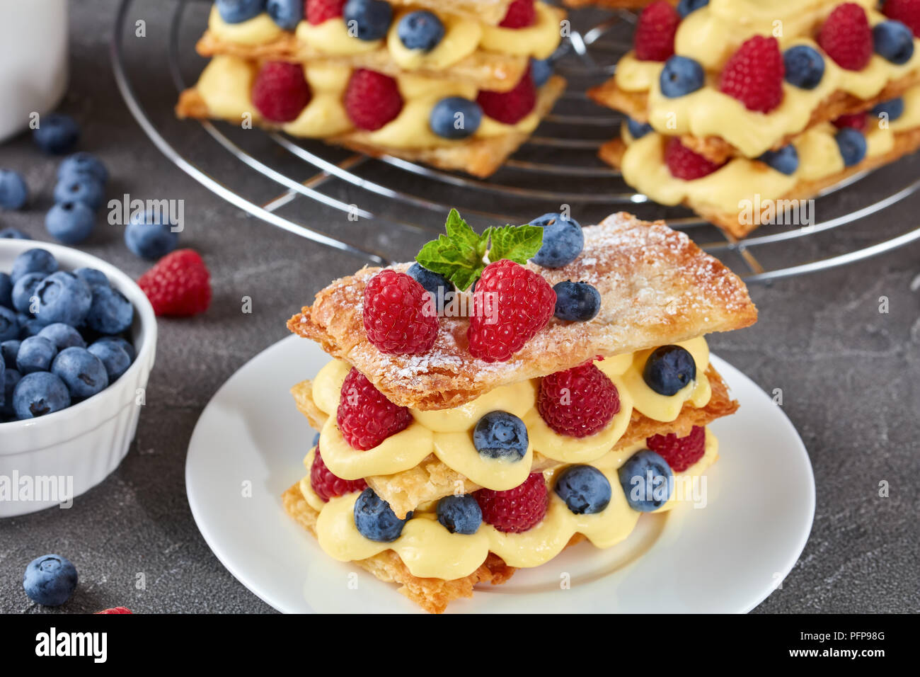 Le Francais Dessert Millefeuille De Pate Feuilletee Et Creme Patissiere Framboises Bleuets Sur Une Plaque Avec De La Creme Fraiche Et Les Baies Sur Une Table En Beton Vi Photo Stock