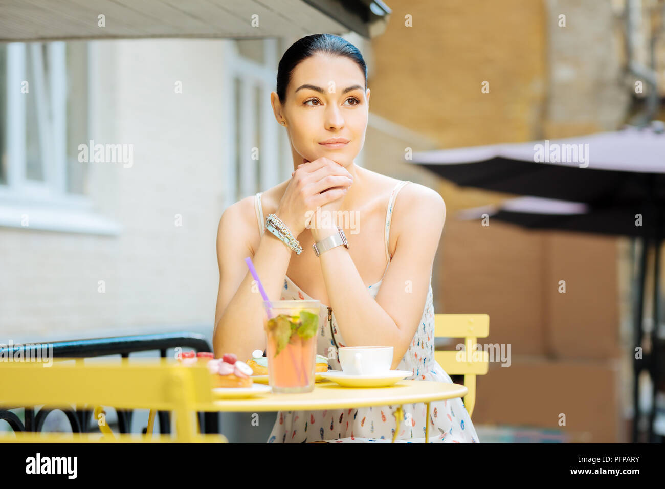 Belle femme assise sur une terrasse de café et en attente d'un(e) ami(e) Banque D'Images