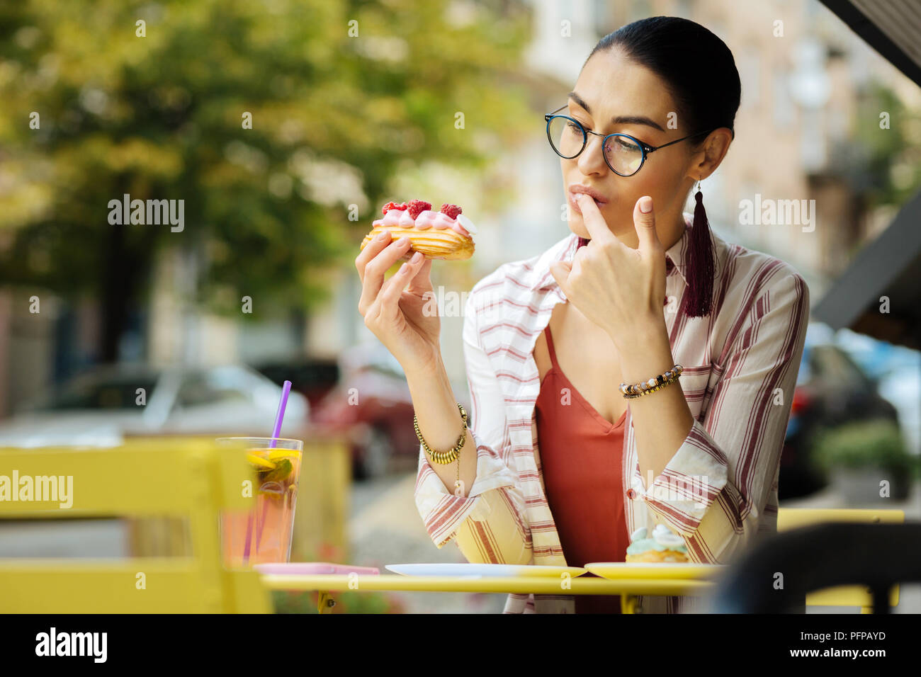 Curieux femme lécher son doigt tout en essayant un nouveau dessert Banque D'Images