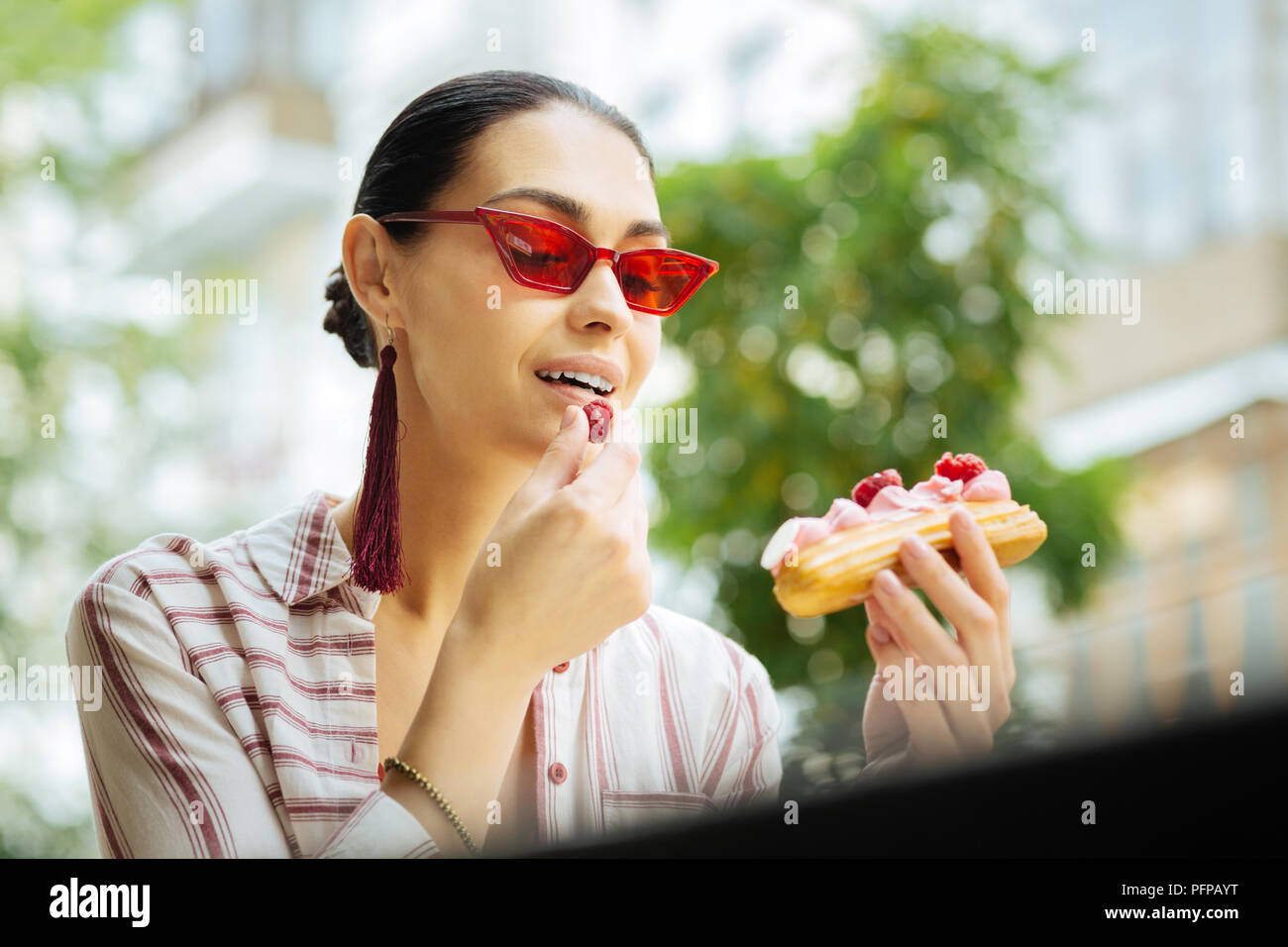 Thoughtful woman eating framboises du dessert et smiling Banque D'Images