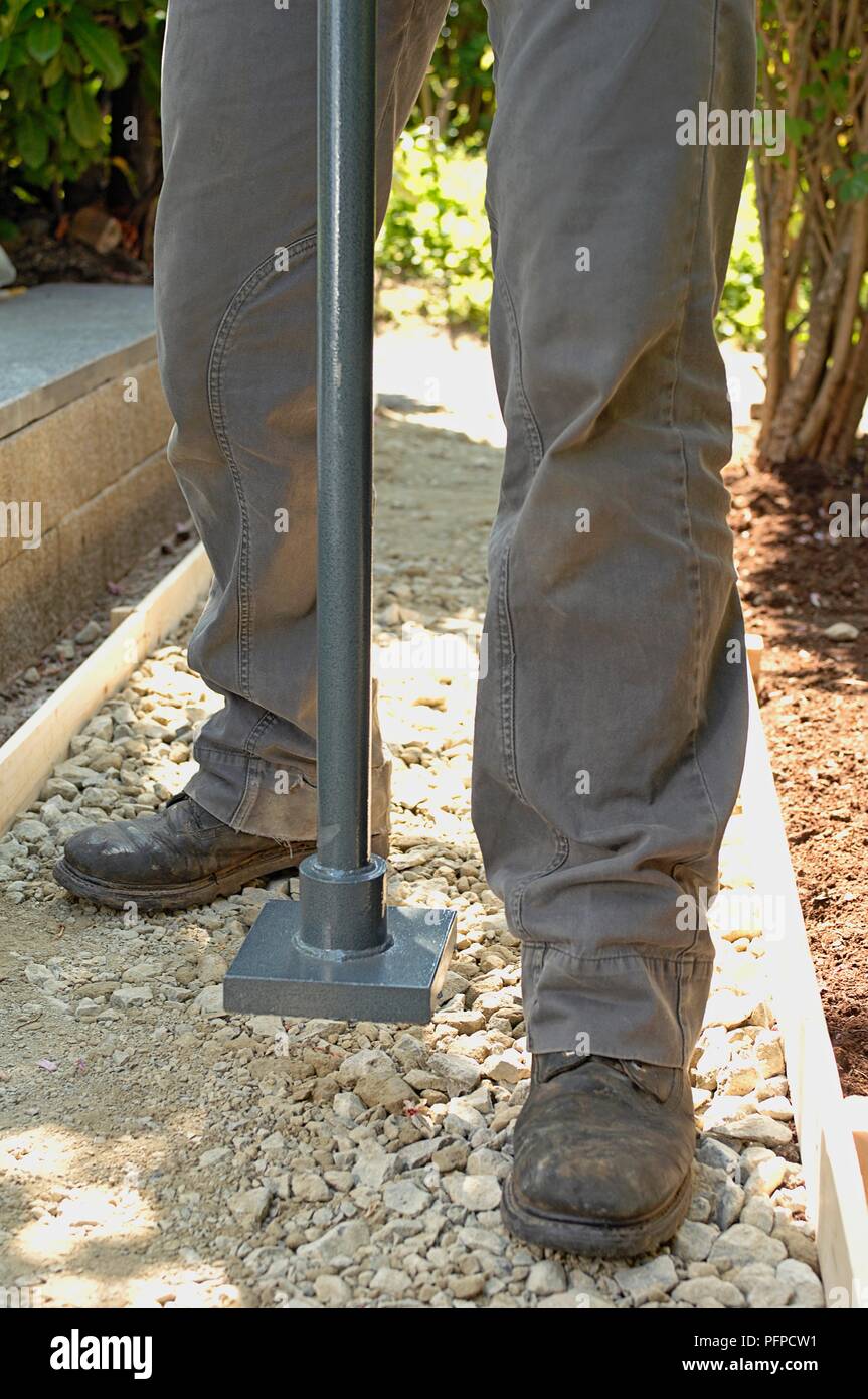 L'homme à l'aide de part de rammer tamp hardcore sur le chemin de jardin, close-up Banque D'Images