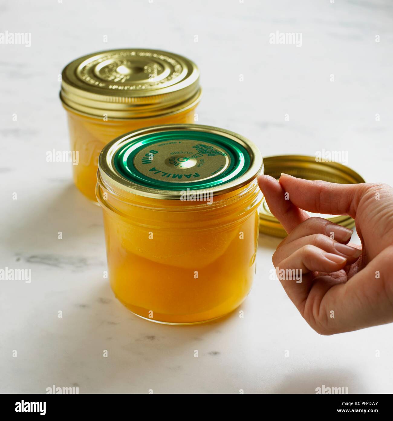 À l'aide d'ongle pour couvercle d'essai à vide sur un bocal de pêches en conserve, close-up Banque D'Images