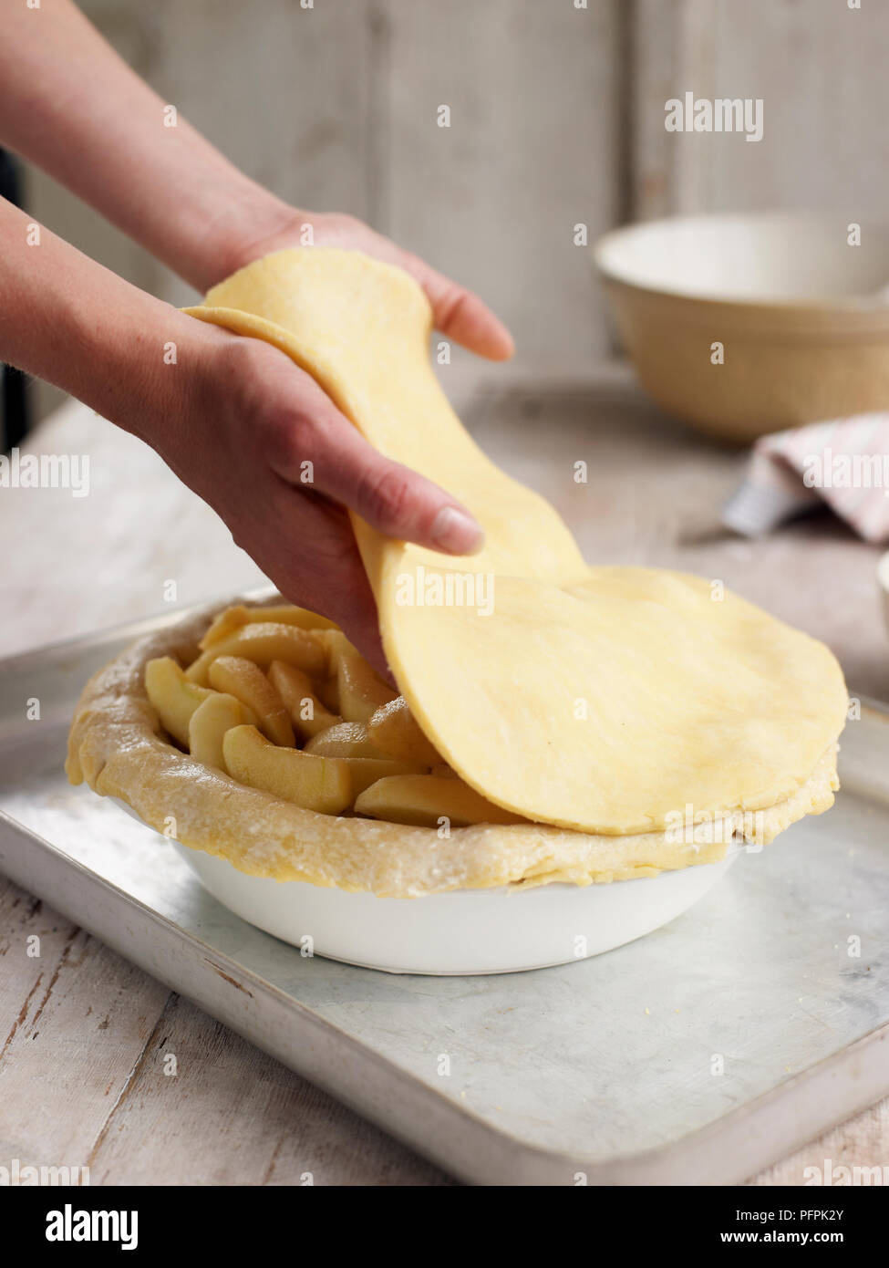 Pose du couvercle de pâte sur la garniture (ce qui fait d'apple pie) Banque D'Images