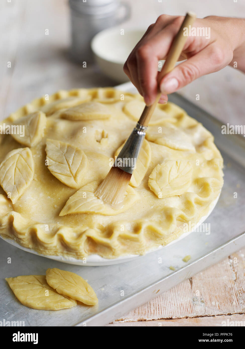 Le brossage à motifs de feuilles de pâte à tarte avec de l'eau Banque D'Images