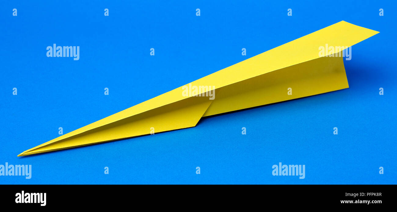 Avion en papier jaune sur fond bleu Banque D'Images