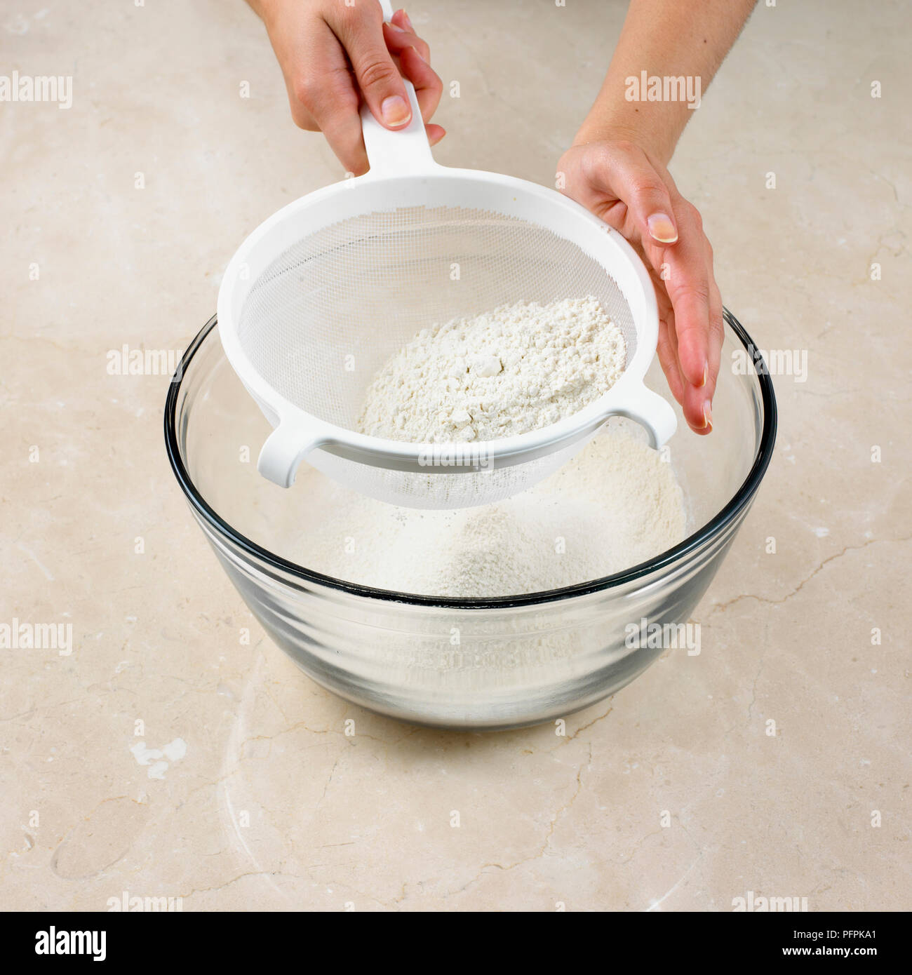 Tamiser la farine dans un récipient Banque D'Images