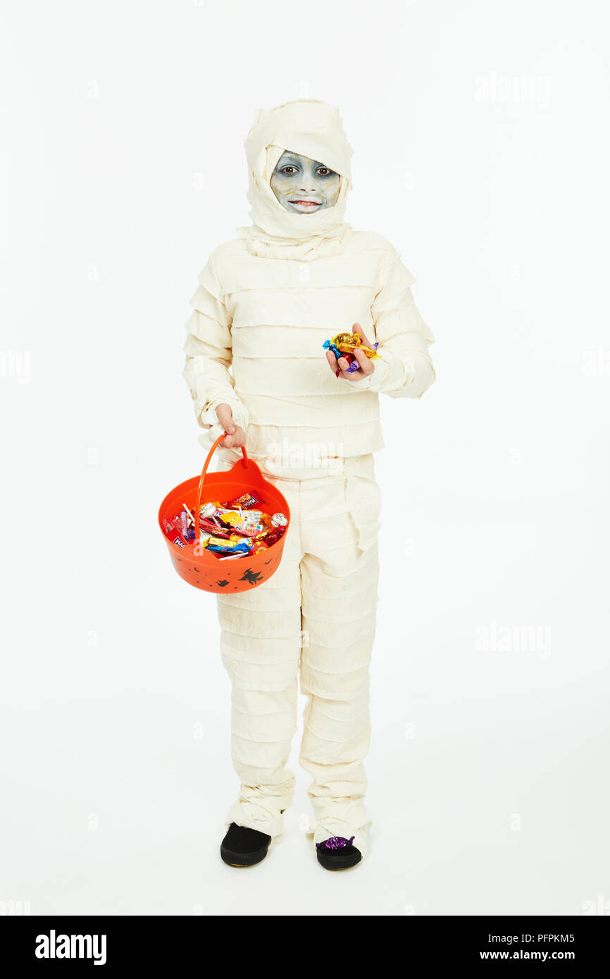 Enfant habillé comme une momie pour l'Halloween avec un trick-or-treat bucket Banque D'Images