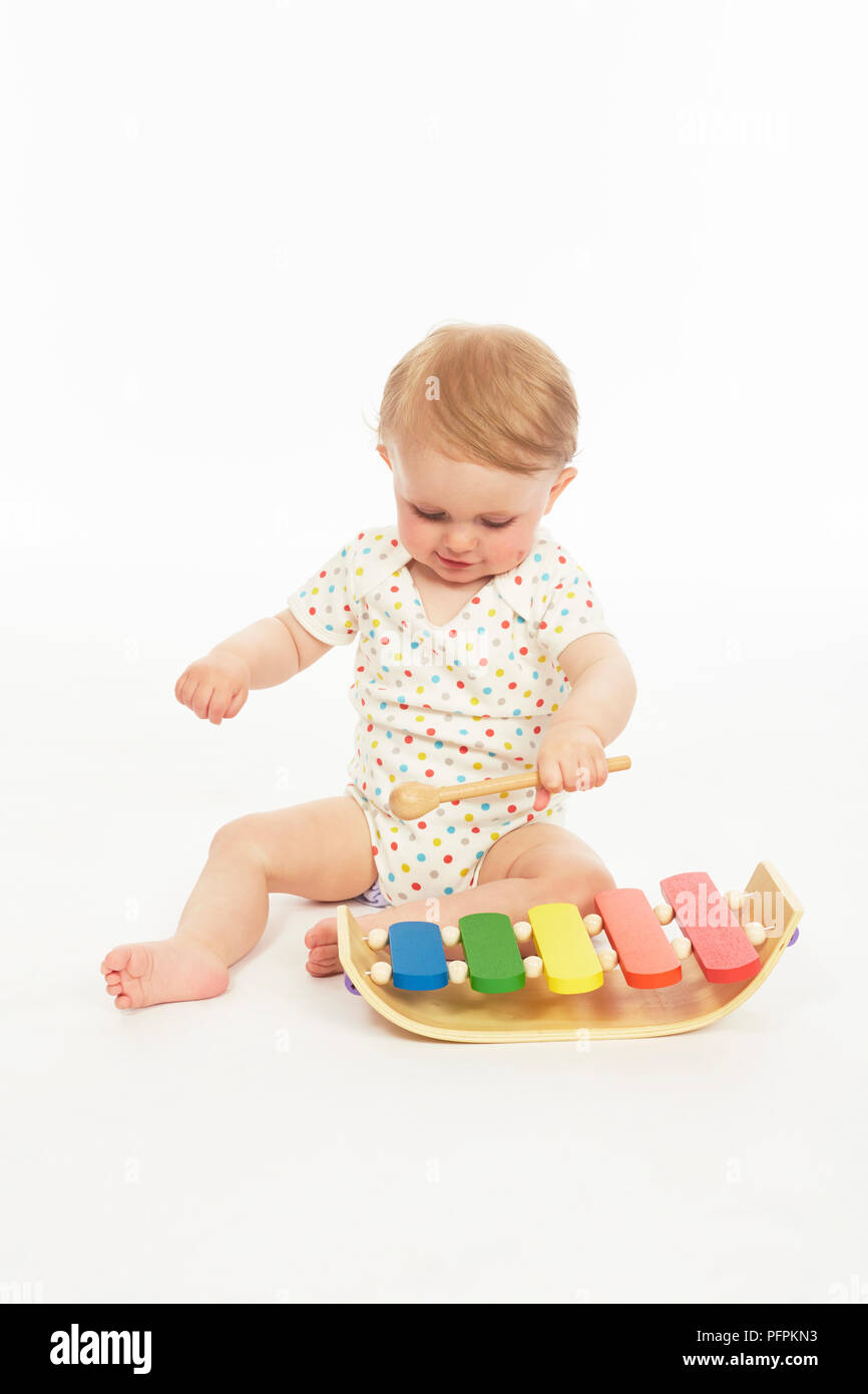 Bébé en monokini assis avec le xylophone (modèle age - 9 mois) Banque D'Images