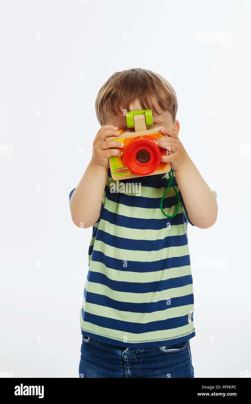 Petit garçon dans stripey haut jouant avec appareil photo (l'âge du modèle - 2 ans) Banque D'Images