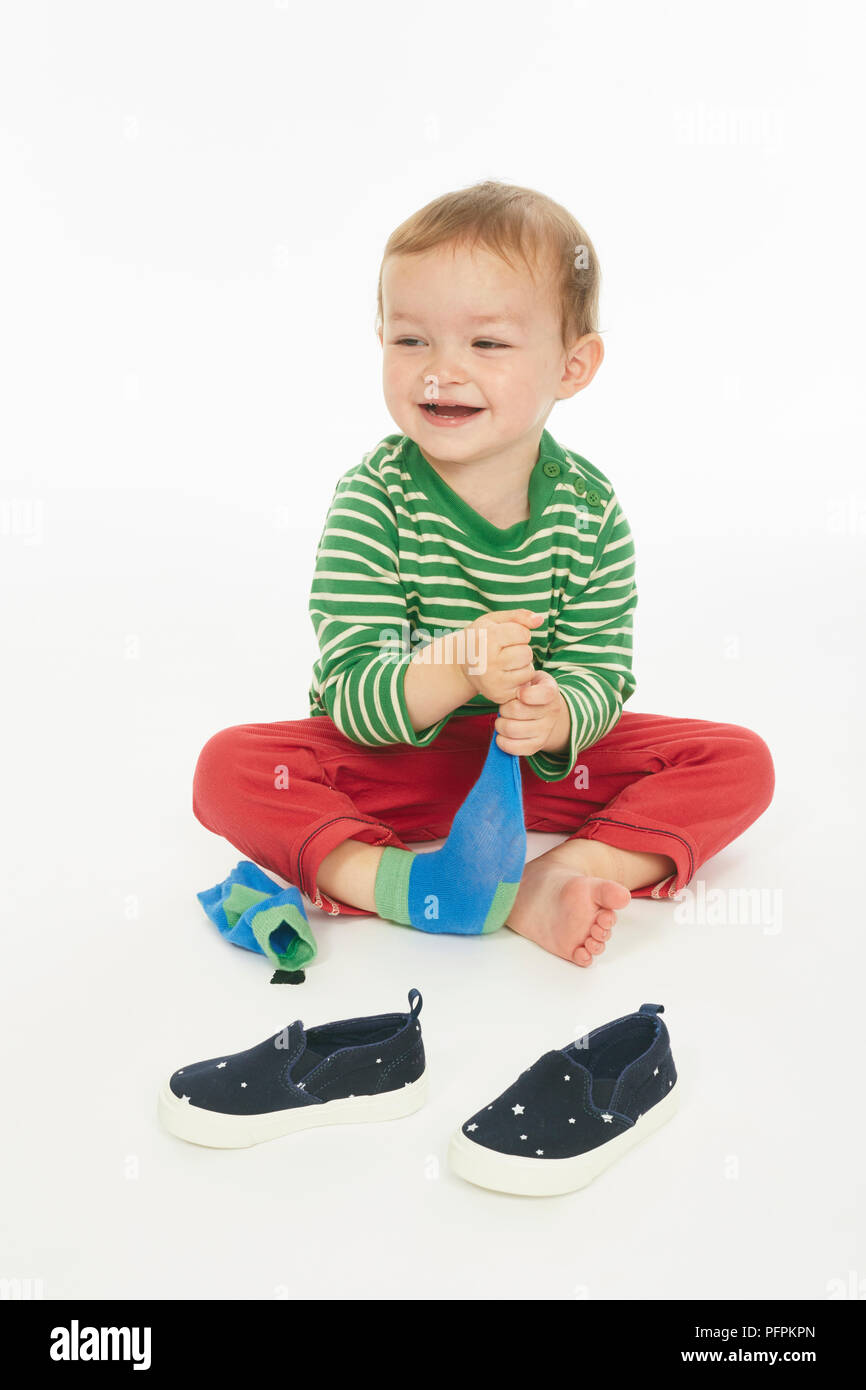 Petit garçon en vert stripey haut assis, le décollage des chaussures et des  chaussettes (Modèle âge - 22 mois Photo Stock - Alamy