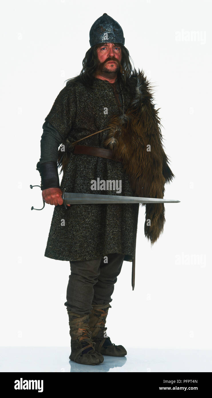 Un homme portant un costume de Viking pantalon long, une chemise et Tunique ceinturée et une peau d'animal utilisé comme un manteau drapé sur son épaule Banque D'Images