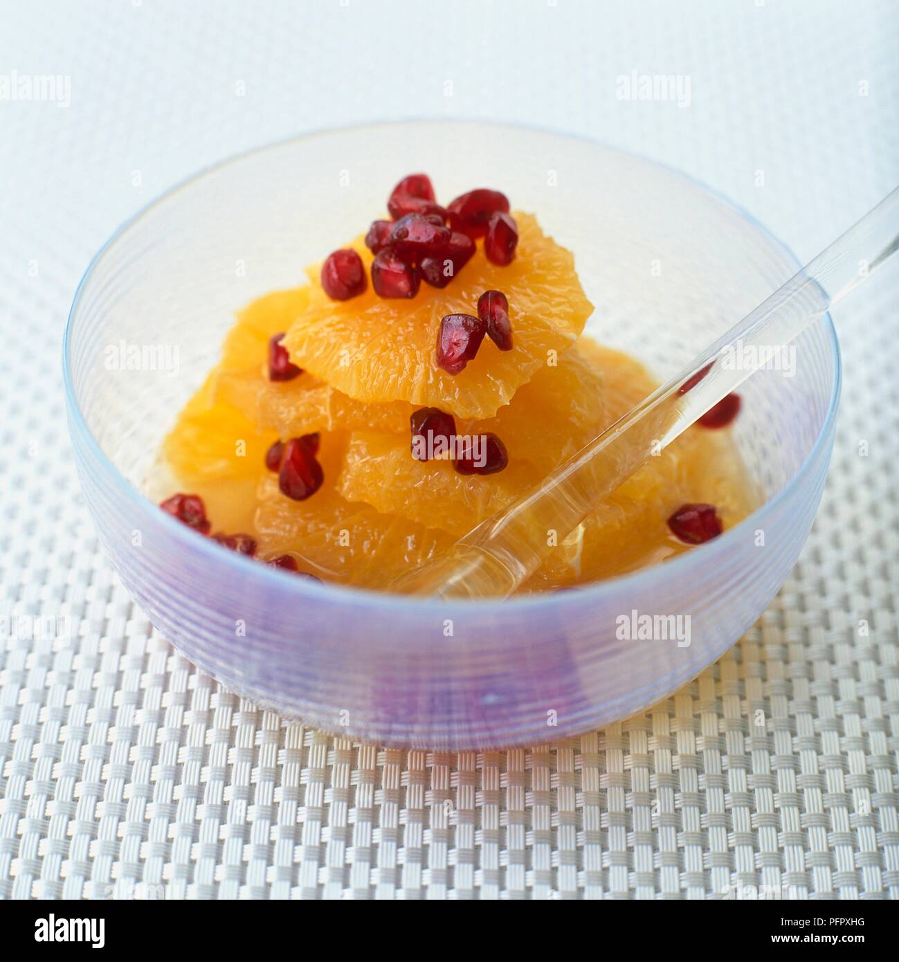 Orange en tranches et pomegranite graines dans un bol avec une cuillère à dessert Banque D'Images