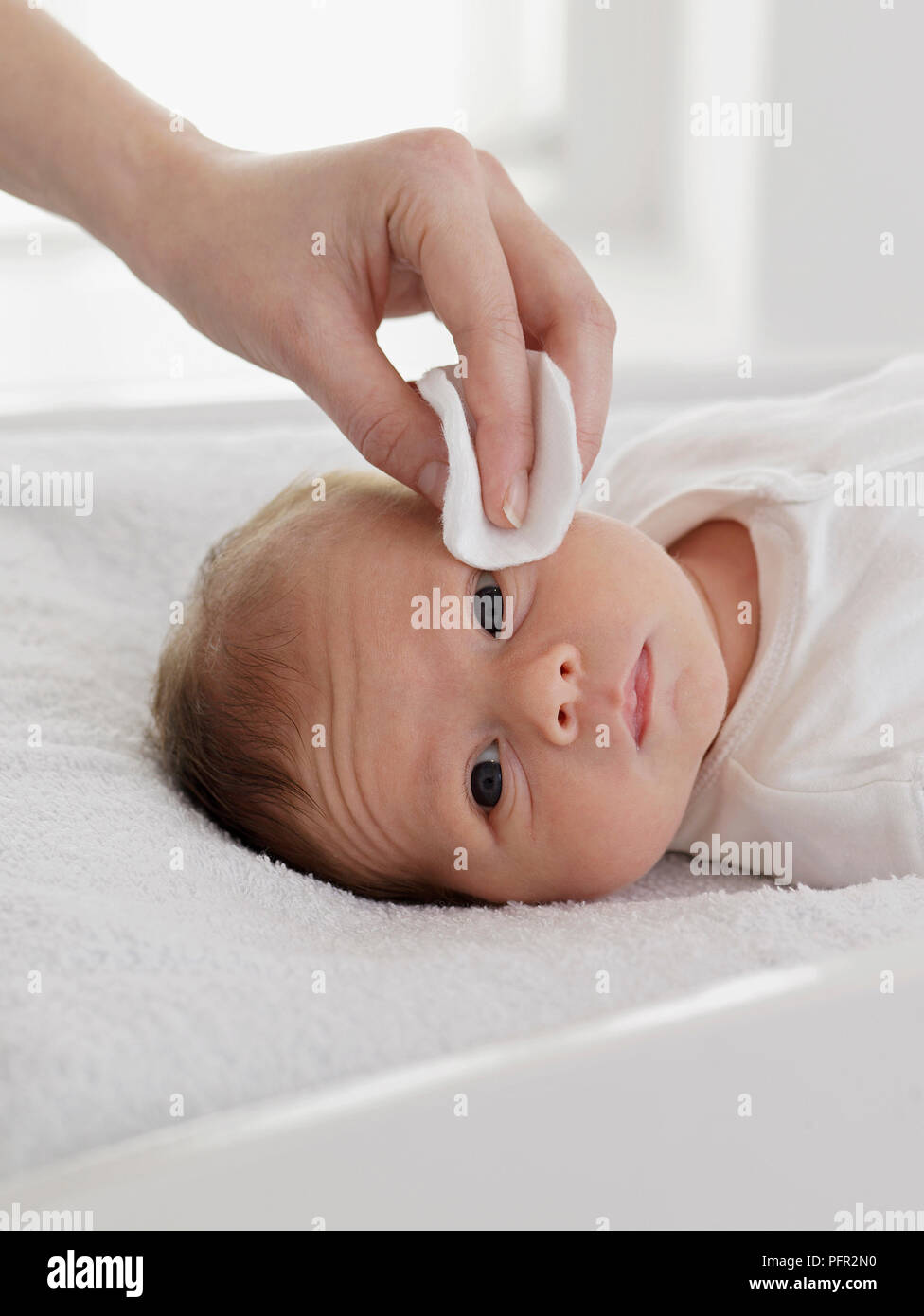 Baby Girl's eye de nettoyage avec un coton, 6 semaines Banque D'Images