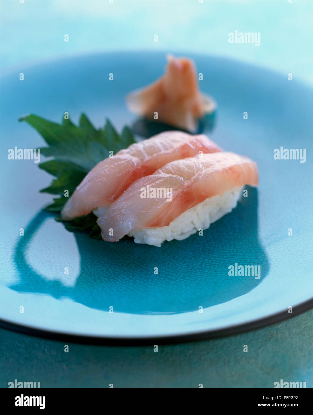 Le vivaneau nigri sushi (Nigirizushi) servi avec des feuilles de wasabi et gingembre mariné sur blue plate, close-up Banque D'Images