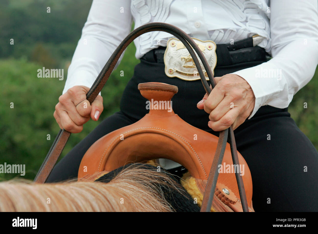 Femme à cheval tenant tête au-dessus de la corne en cuir selle western, close-up Banque D'Images