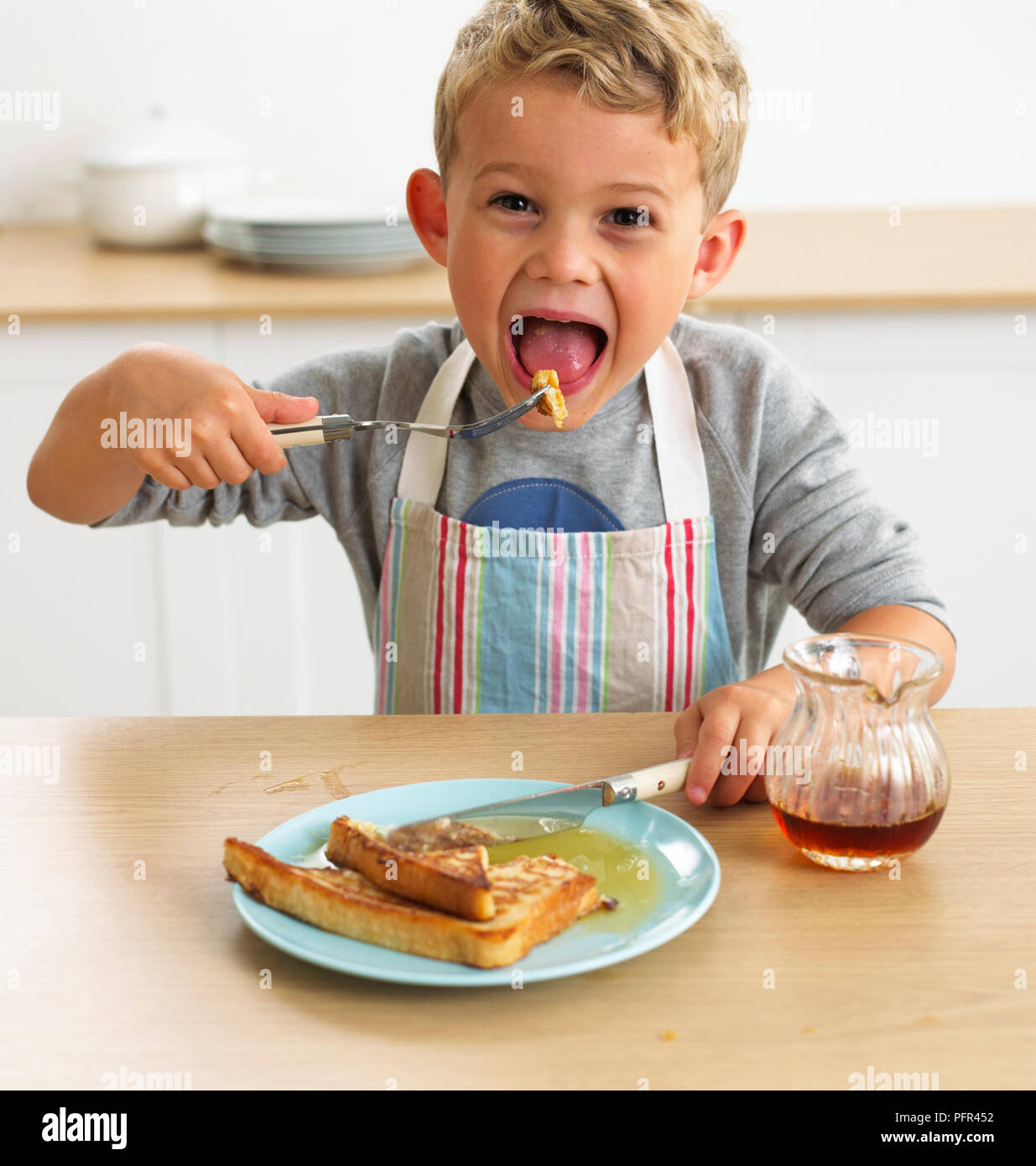 Boy eating eggy pain avec de l'érable, 4 ans Banque D'Images