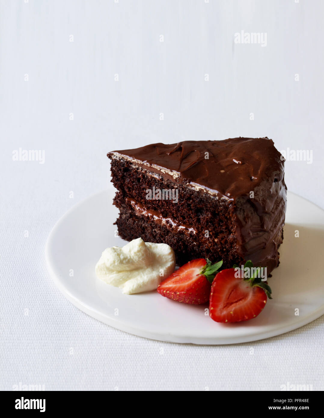 Morceau de gâteau au chocolat sans gluten sur une plaque avec deux fraises Banque D'Images