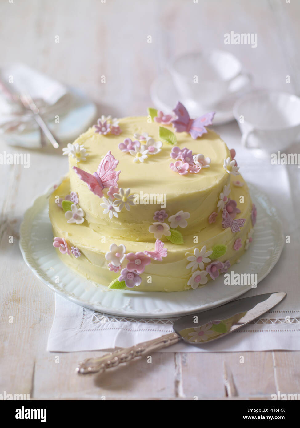 Gâteau glacé à deux niveaux décoré de fleurs et papillons faits de cerise Banque D'Images