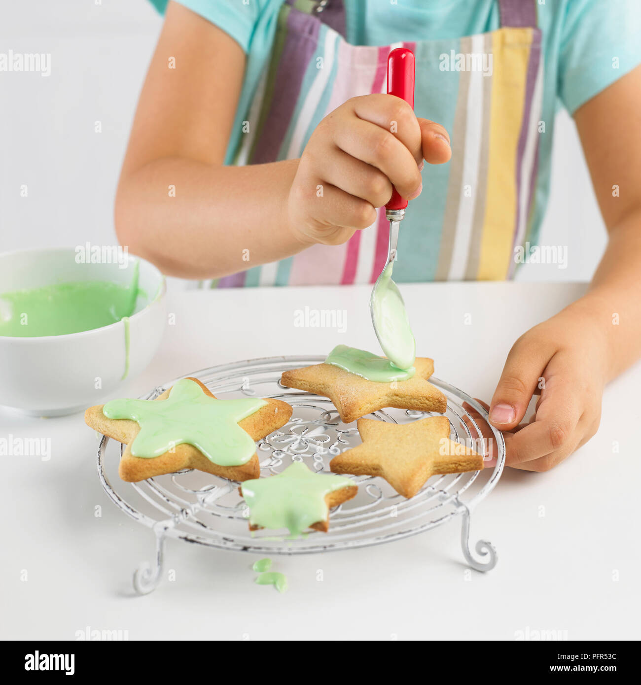 Girl decorating cookies en forme d'étoile avec du glaçage, 5 ans Banque D'Images
